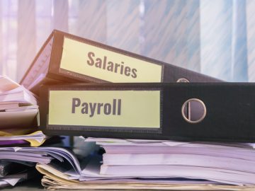 Payroll and salaries folders stack with label on black binder on paperwork documents summary report, HR-human resources business and bookkeeping accountancy concept in busy offices